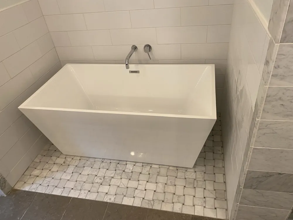 A freestanding soaking tub on a basketweave tile floor