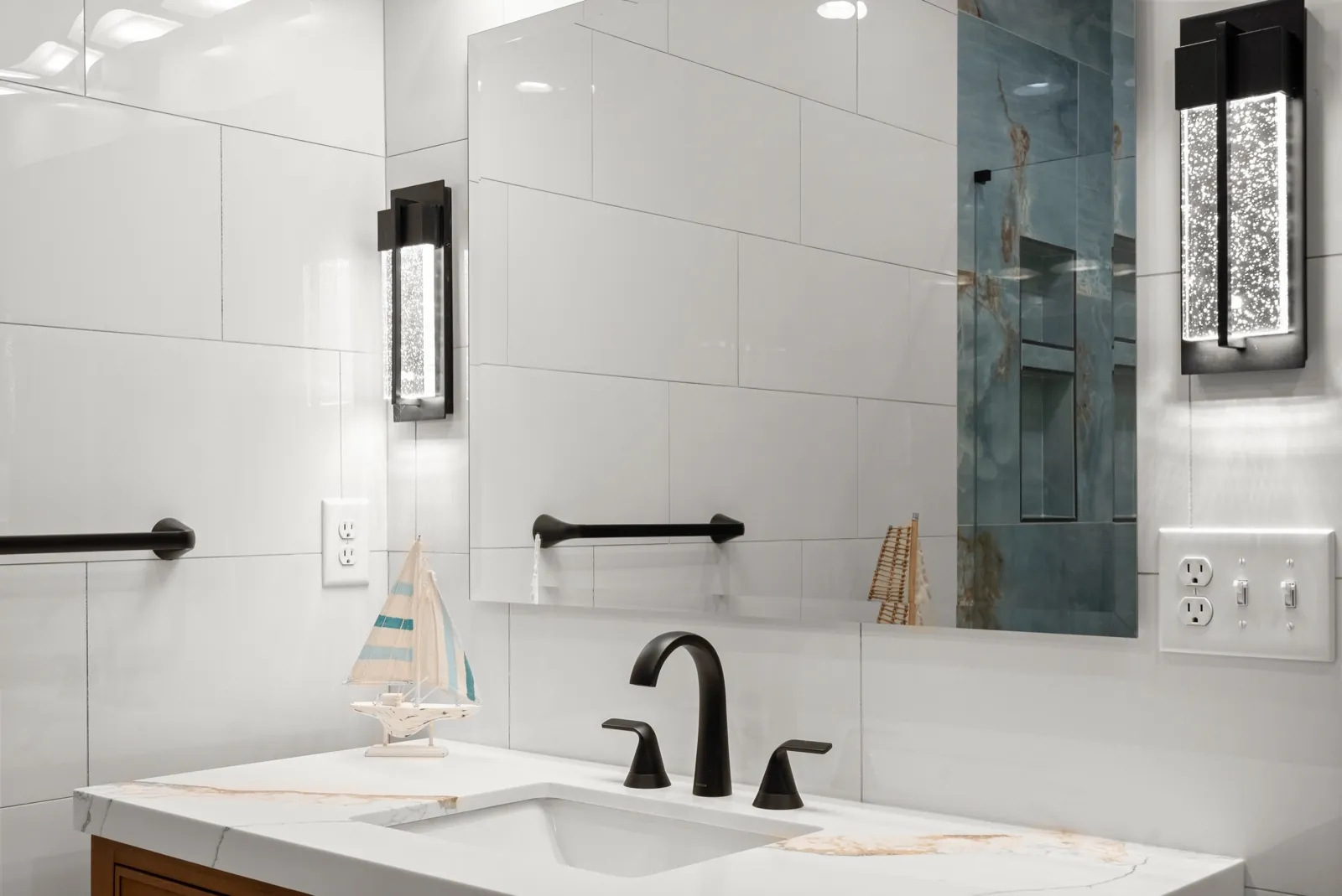 Bathroom remodeling for Gainesville, GA homeowners: a JWAC bathroom with large white tile, a black faucet and a lit sconce