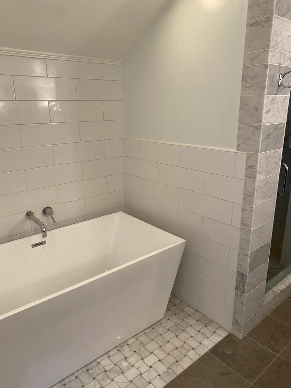 A freestanding tub set against white wall tile