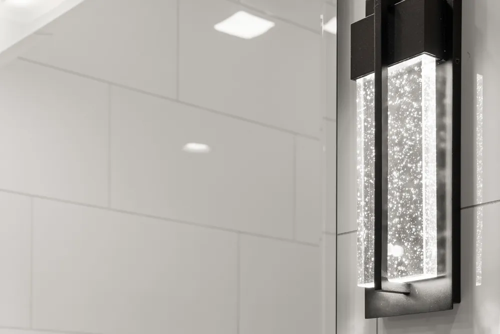 Large white wall tile with a lit wall sconce