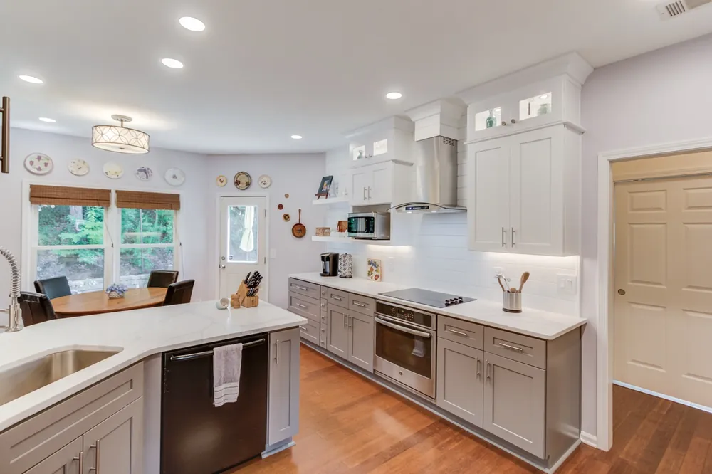 Gray lower cabinets, a wall hood and lit upper cabinets